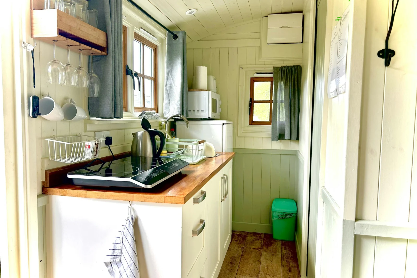 Kitchen with small hob, sink, kettle, fridge/freezer, microwave, various utensils and windows
