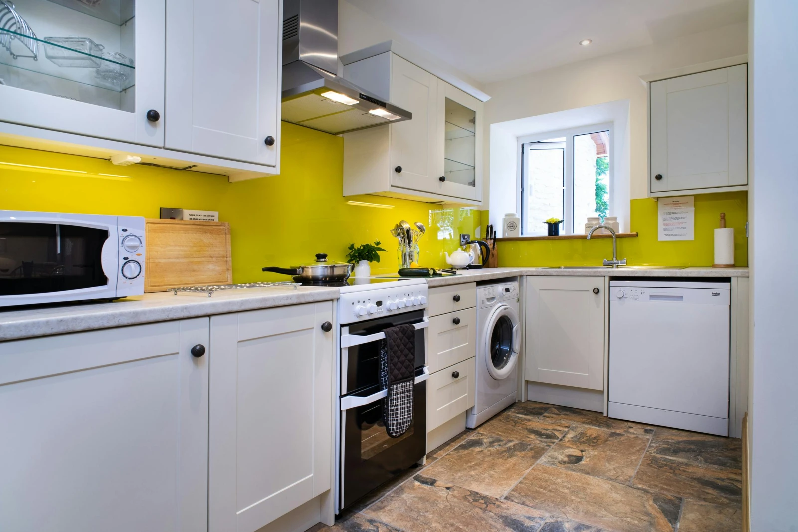 Fitted kitchen with cooker, washing machine, dishwasher, microwave, kettle and window
