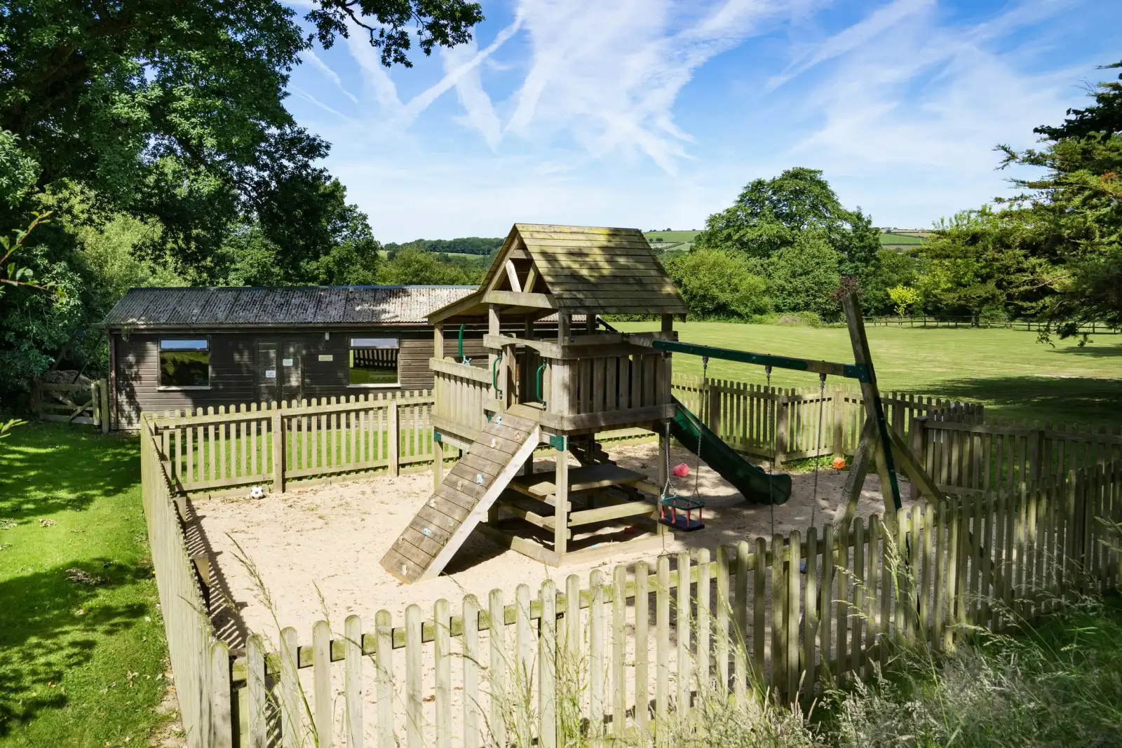 Play area with play tower, lawns and games room for use by guests at Towy Cottage