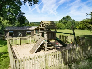 Play area with play tower, lawns and games room for use by guests at Towy Cottage