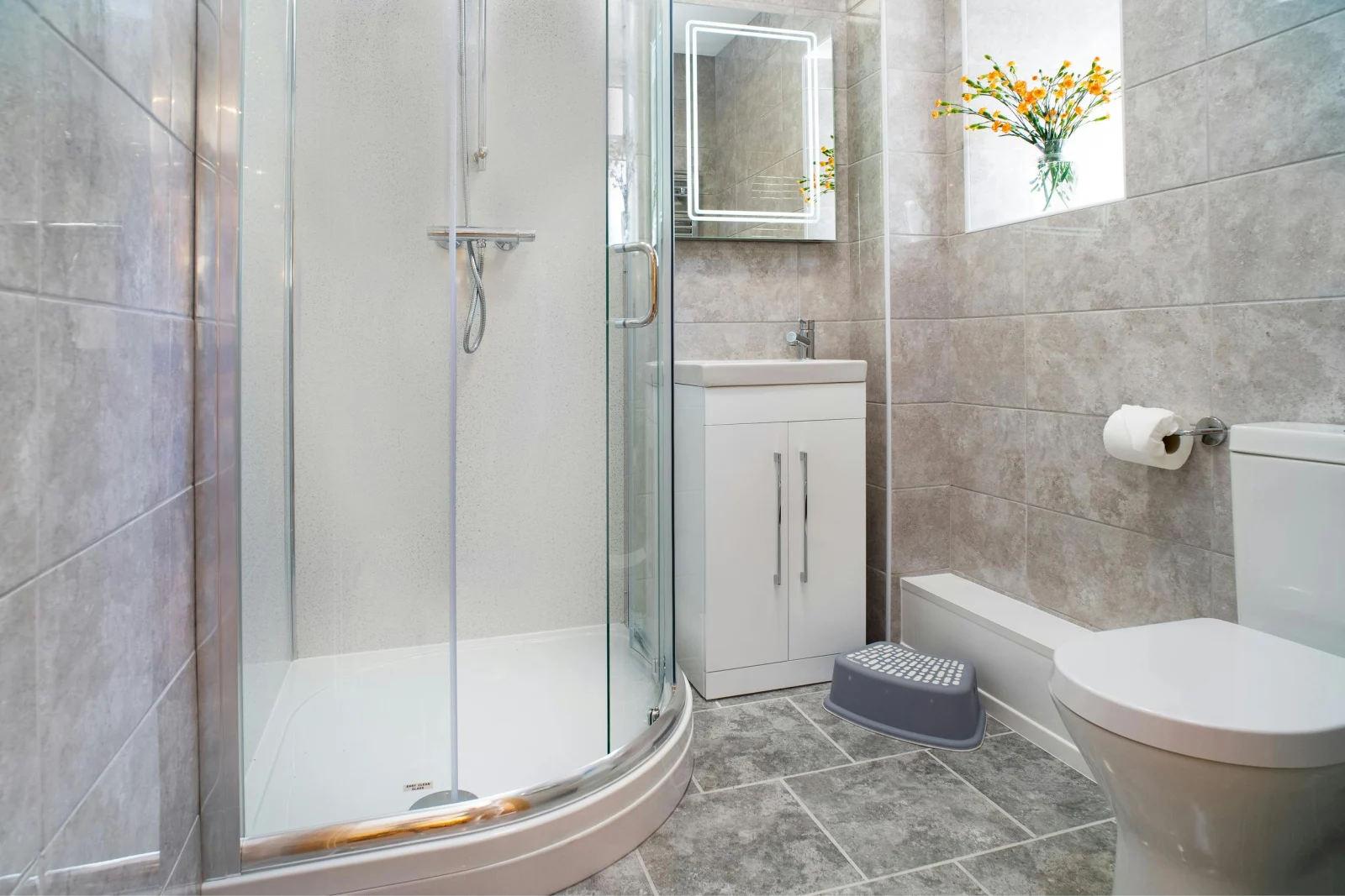 Fully tiled ground floor shower room with shower, toilet, washbasin and window