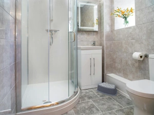 Fully tiled ground floor shower room with shower, toilet, washbasin and window