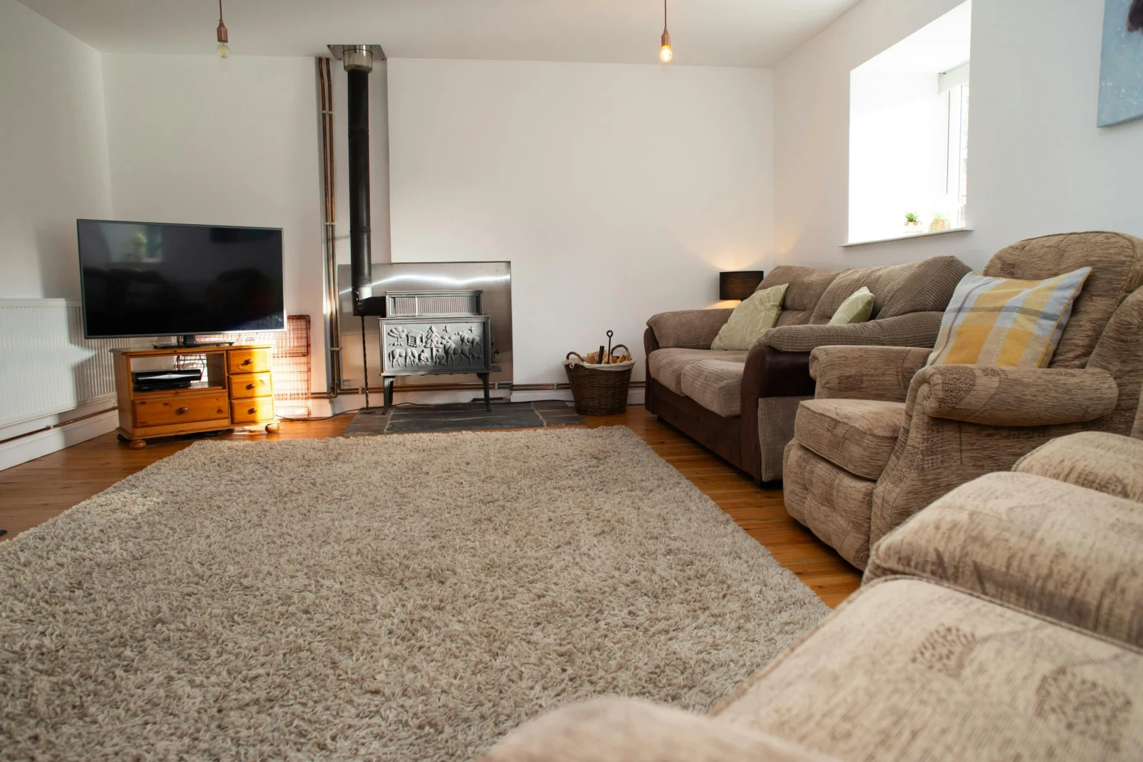 Lounge with sofas, armchairs, log burner and TV on unit