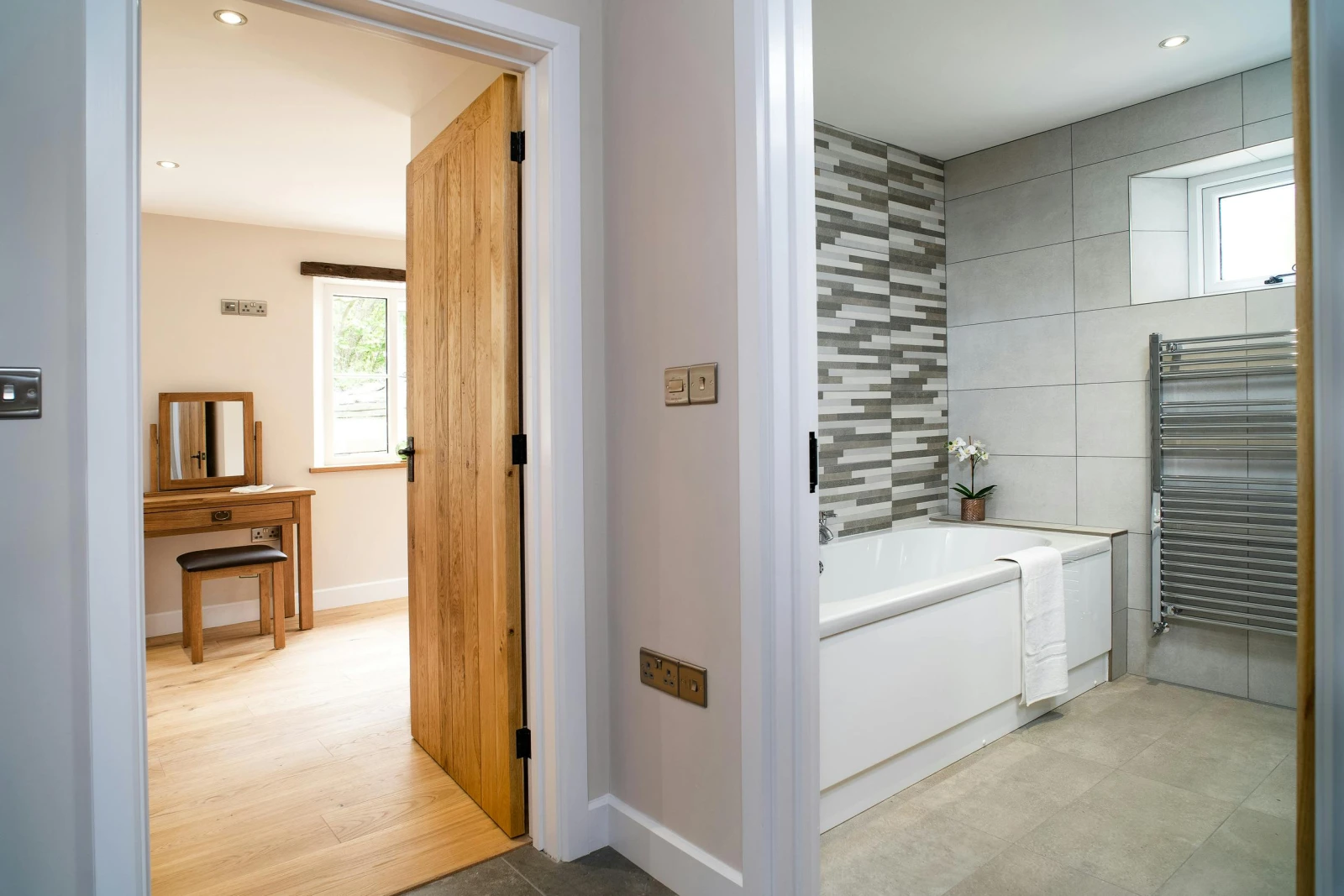 Bathroom with bath, heated towel rail and view through door into bedroom