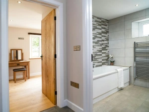 Bathroom with bath, heated towel rail and view through door into bedroom