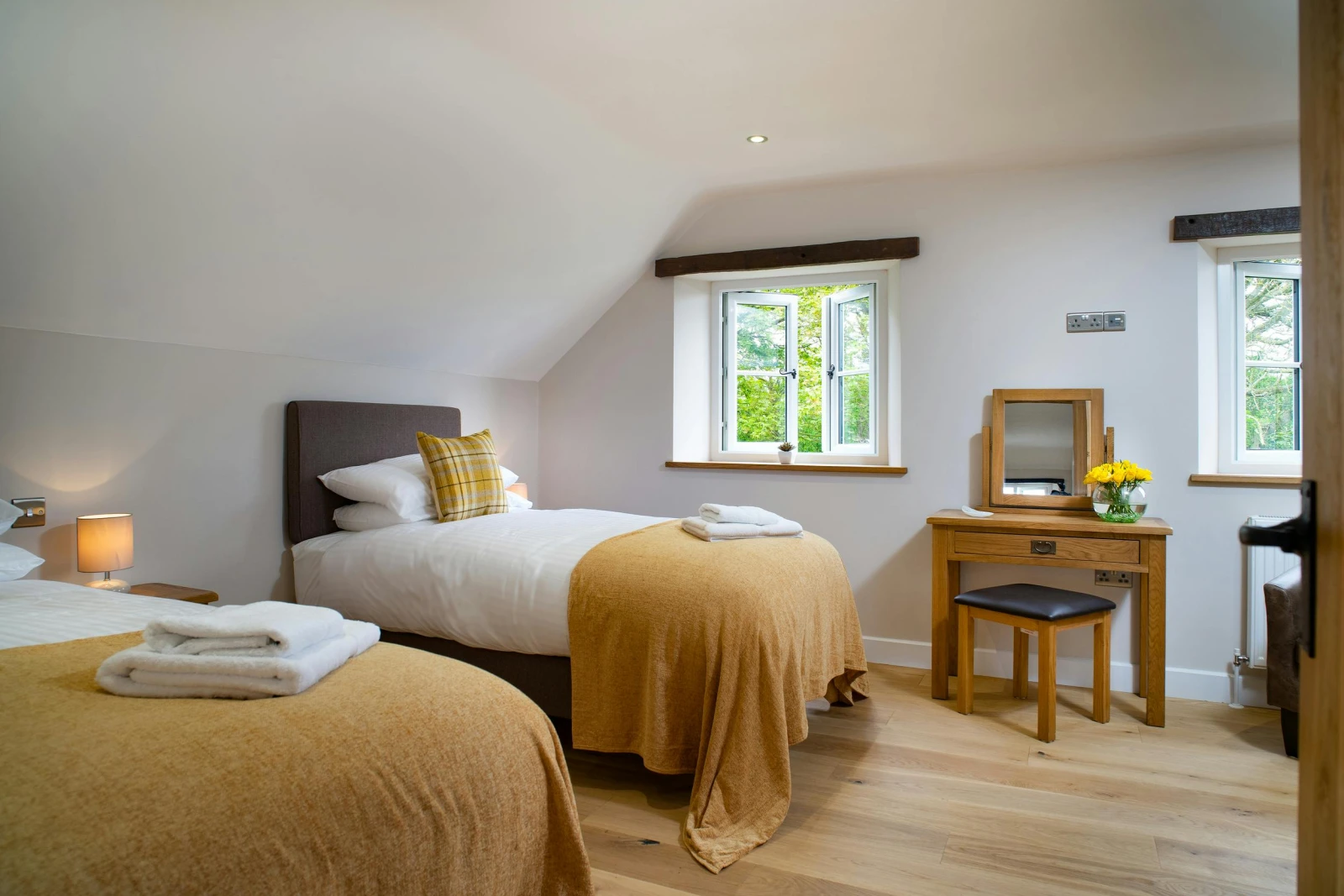 Twin single beds, bedside unit with lamp, dressing table with stool and mirror, two windows