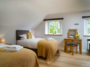 Twin single beds, bedside unit with lamp, dressing table with stool and mirror, two windows