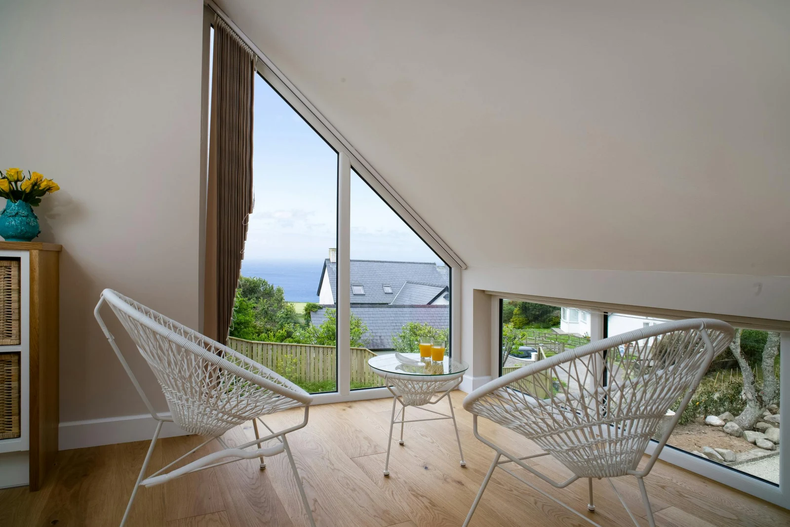 Seating area in bedroom with small table and two chairs and window with sea view