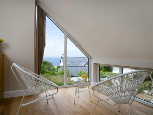 Seating area in bedroom with small table and two chairs and window with sea view