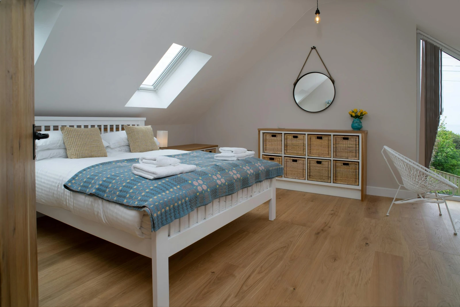Bedroom with bed, drawers, velux windows and window with distant view of the sea