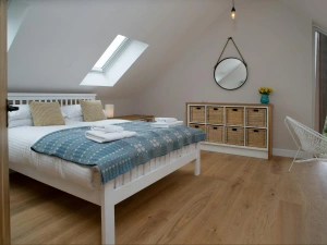 Bedroom with bed, drawers, velux windows and window with distant view of the sea