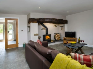 Living room with fireplace, log burner, sofa, TV on unit and coffee table