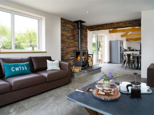Living room with sofa, log burner, coffee table and view into kitchen
