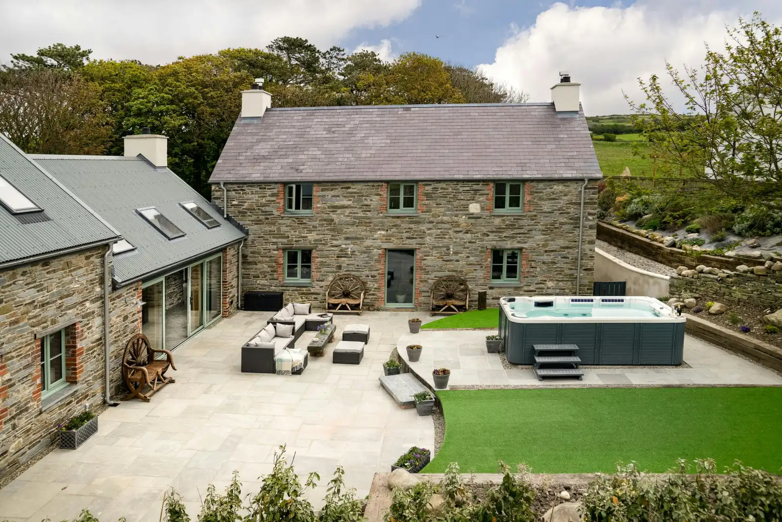 Outside view of Towyn Farmhouse with hot tub, outside seating area and lawn