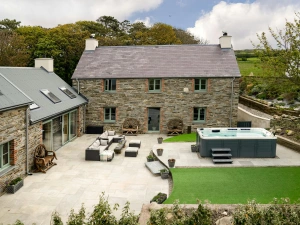 Outside view of Towyn Farmhouse with hot tub, outside seating area and lawn