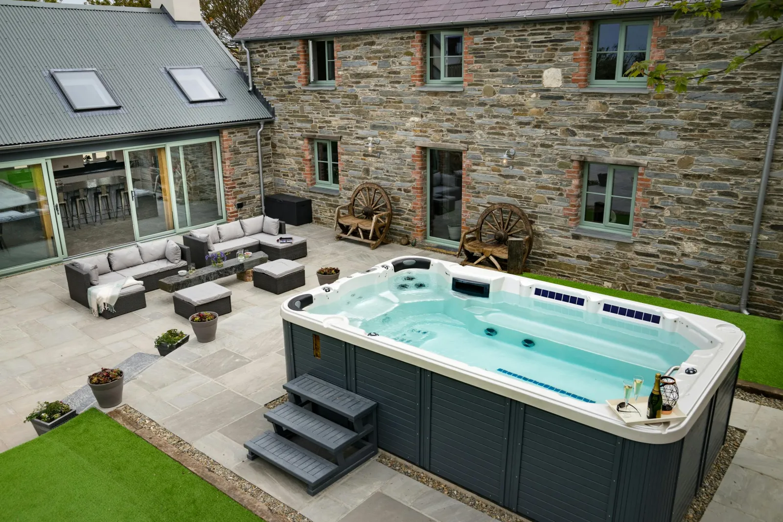 Outside view of Towyn Farmhouse with hot tub, outside seating area and lawn