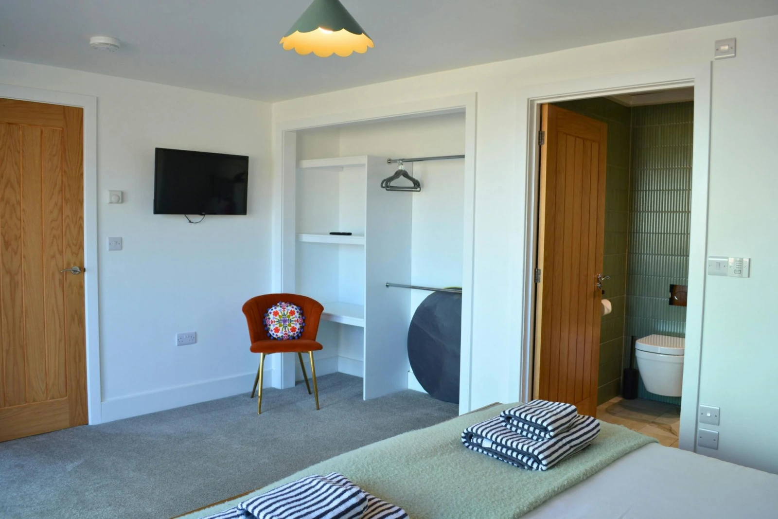 View of the open wardrobe, chair and wall mounted TV