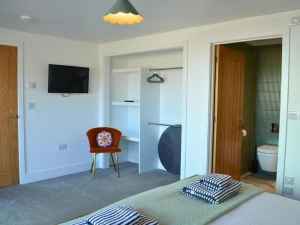 View of the open wardrobe, chair and wall mounted TV