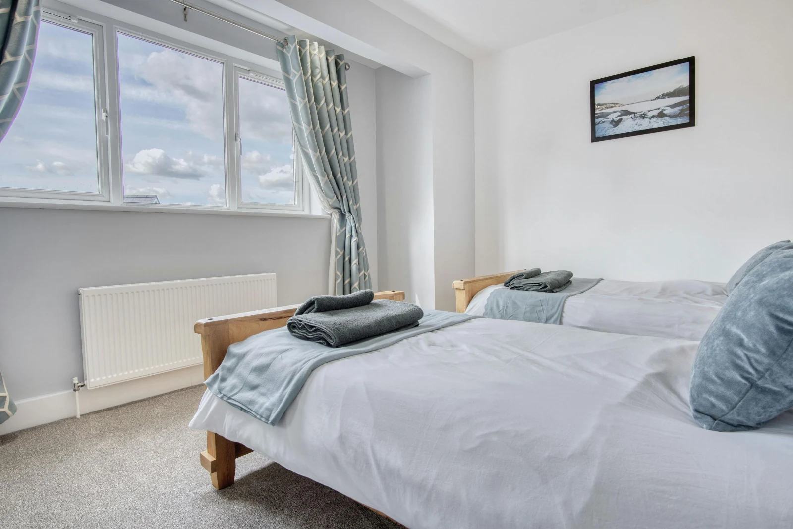 Twin single beds, towels folded on the end of the beds, radiator and window