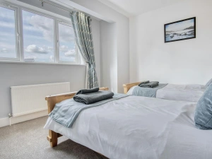 Twin single beds, towels folded on the end of the beds, radiator and window