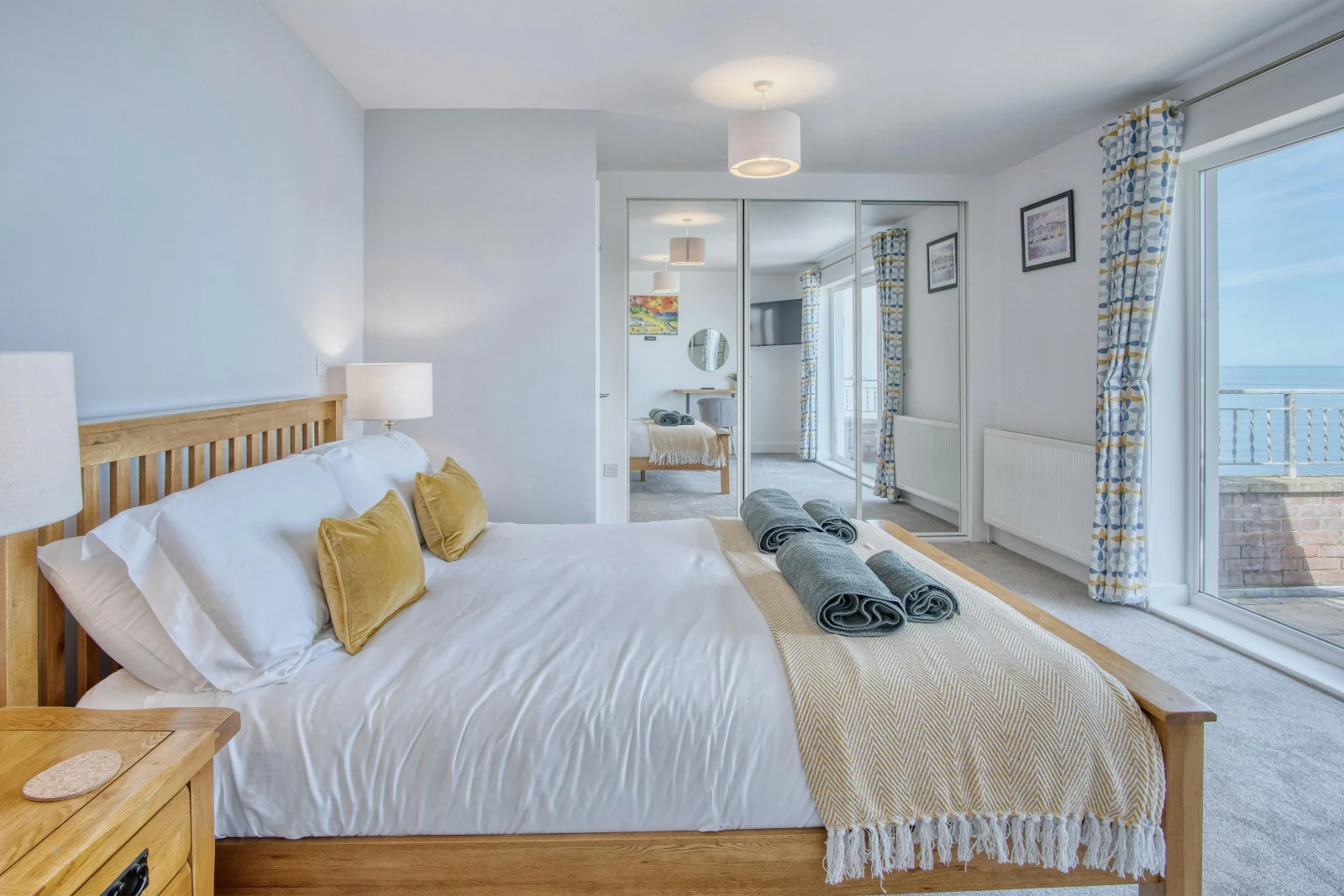Patio doors to the balcony from the king size bedroom, bed, bedside drawers with lamps and fitted wardrobes