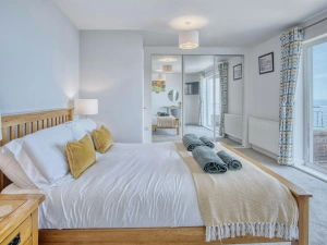 Patio doors to the balcony from the king size bedroom, bed, bedside drawers with lamps and fitted wardrobes