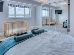 King size bedroom, towels on the bed, cot, window and fitted wardrobe