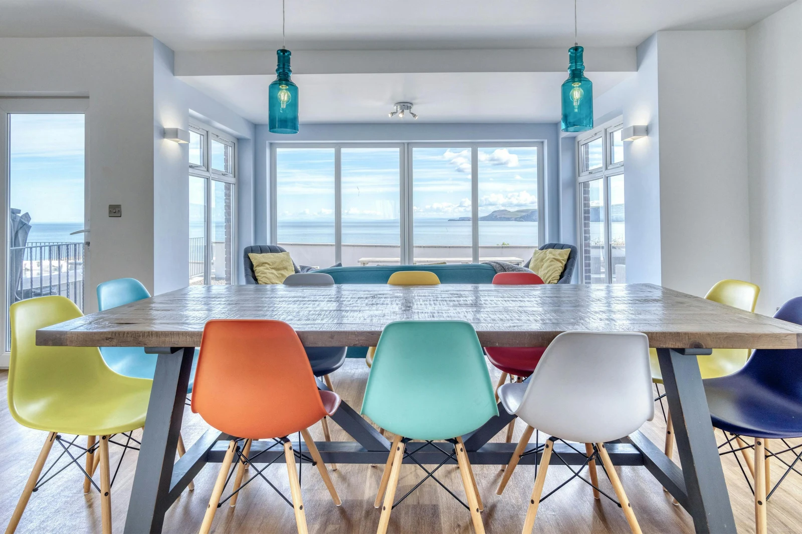 Dining table and chairs for 10 with 2 chairs in the background looking out to the sea