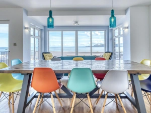 Dining table and chairs for 10 with 2 chairs in the background looking out to the sea