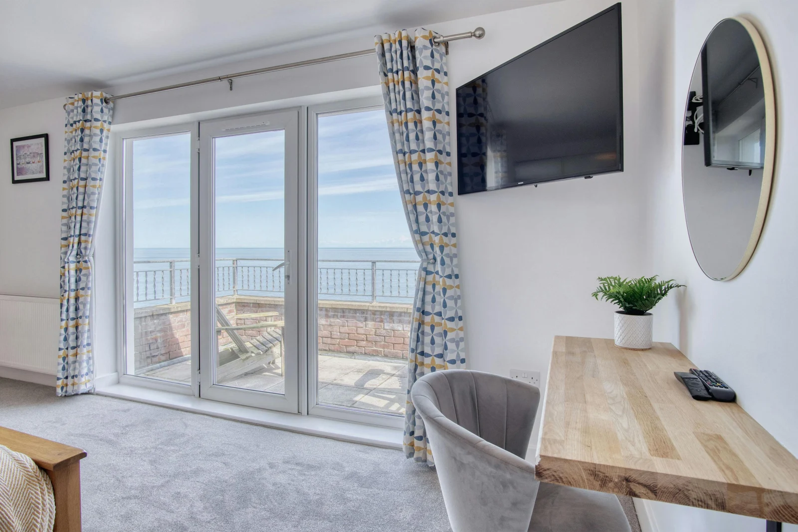 Patio doors in the master bedroom to balcony, chair and dressing table and wall mounted TV
