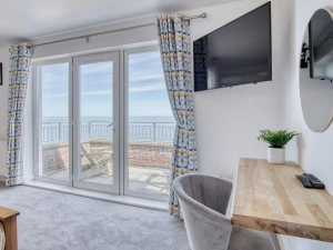 Patio doors in the master bedroom to balcony, chair and dressing table and wall mounted TV