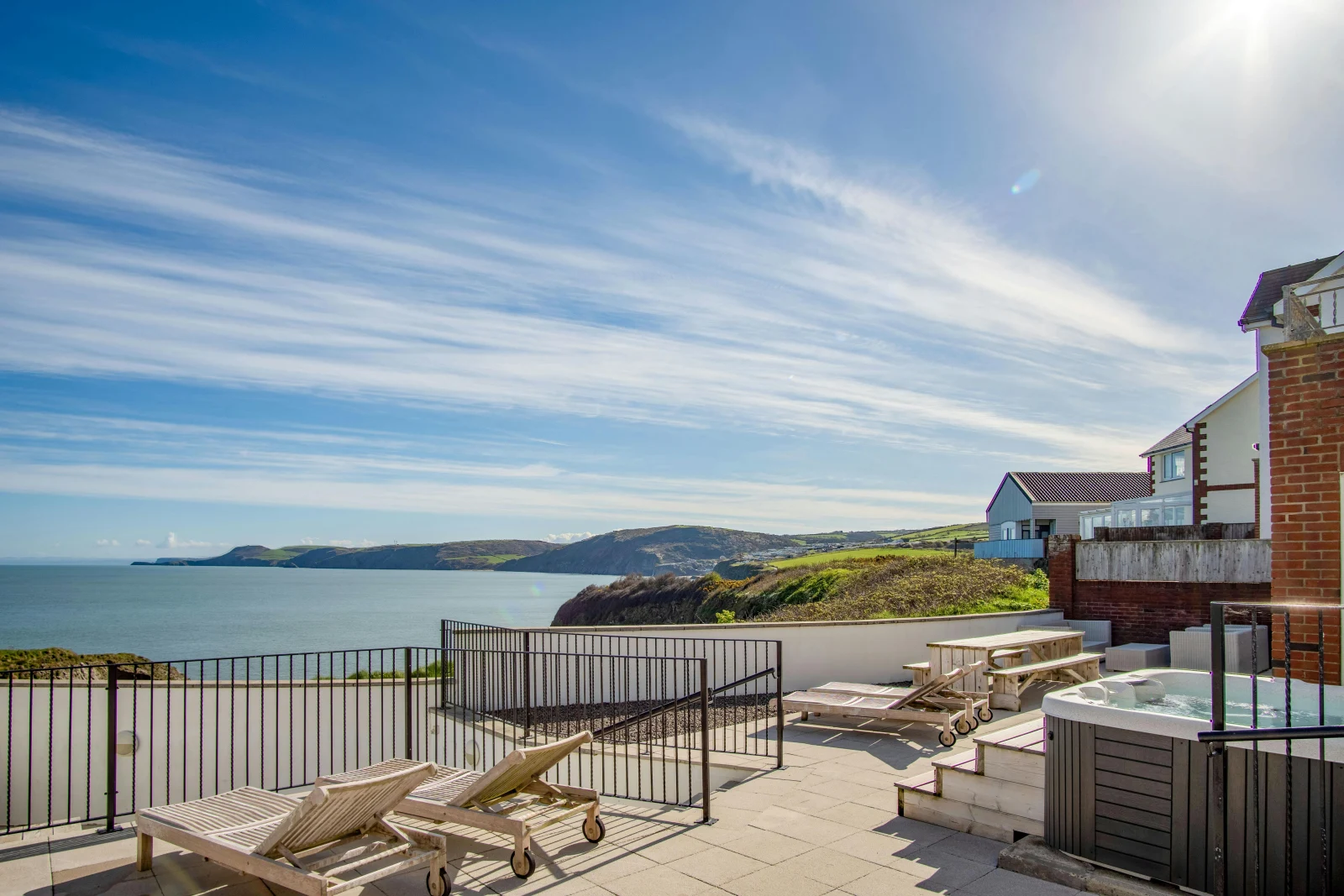 Clifftop Haven patio with seating areas, hot tub and sea and coastline views