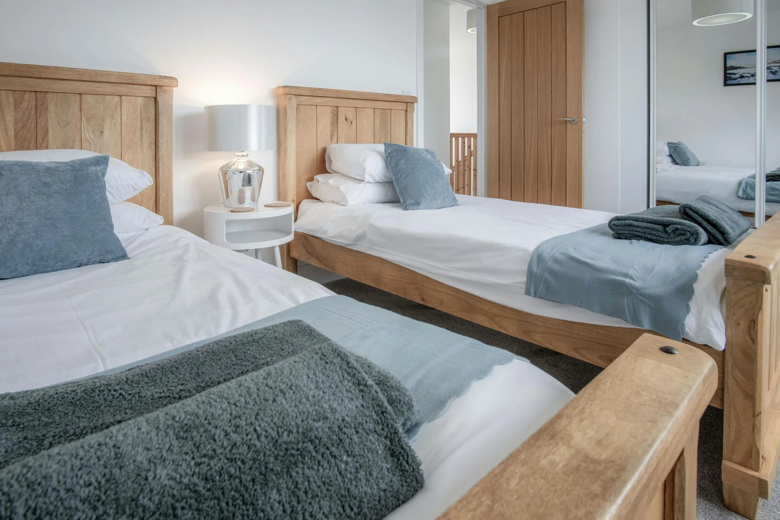 Twin single beds, bedside table with a lamp and fitted wardrobe