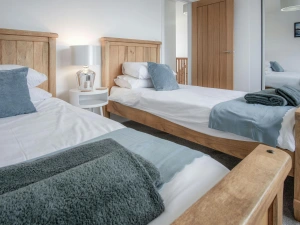 Twin single beds, bedside table with a lamp and fitted wardrobe