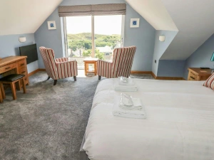 First floor king size bedroom with bed, 2 armchairs facing large window, TV, dressing table