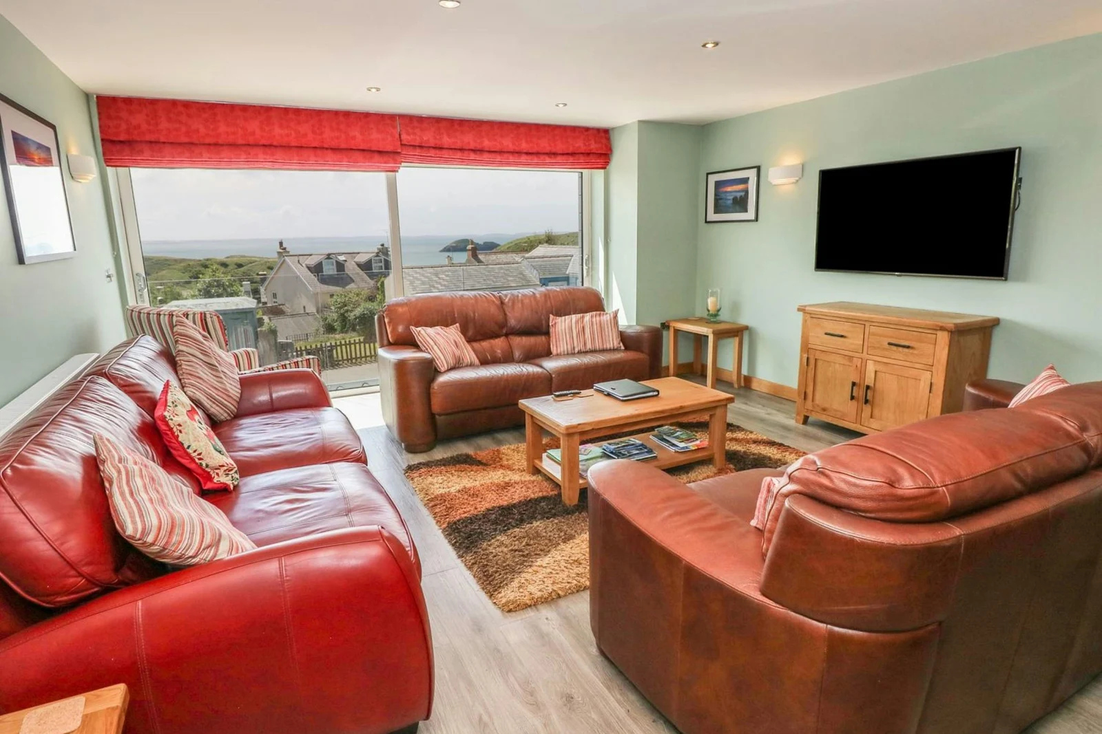 Leather sofas, wall mounted TV, coffee table, small sideboard and big picture window