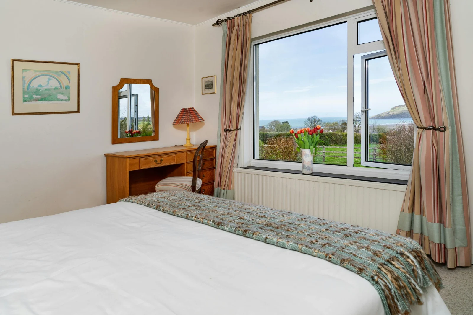 Bedroom with king size bed, dressing table and window with sea views