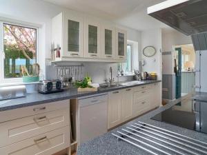 Kitchen with cooker, cooker hood, sink and fitted cupboards