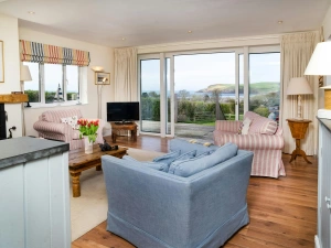 Living area at Dolawel with sofas, armchairs, tv and patio door leading to garden