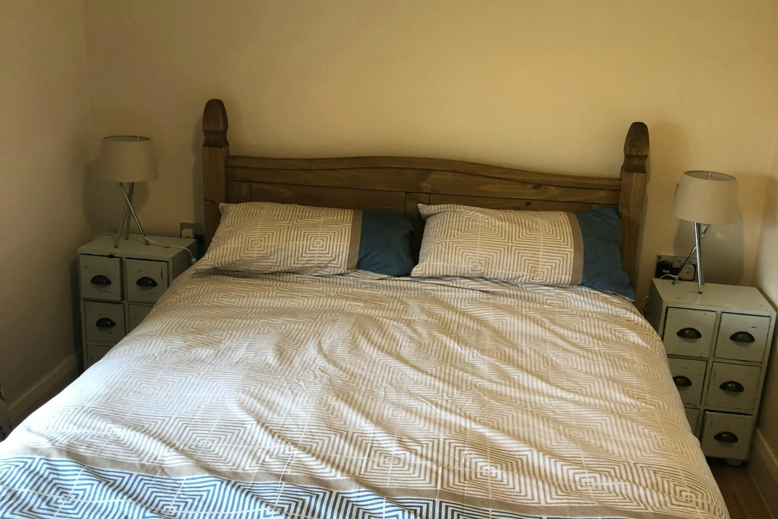 King size bed with bedside drawers and small lamps, picture above bed