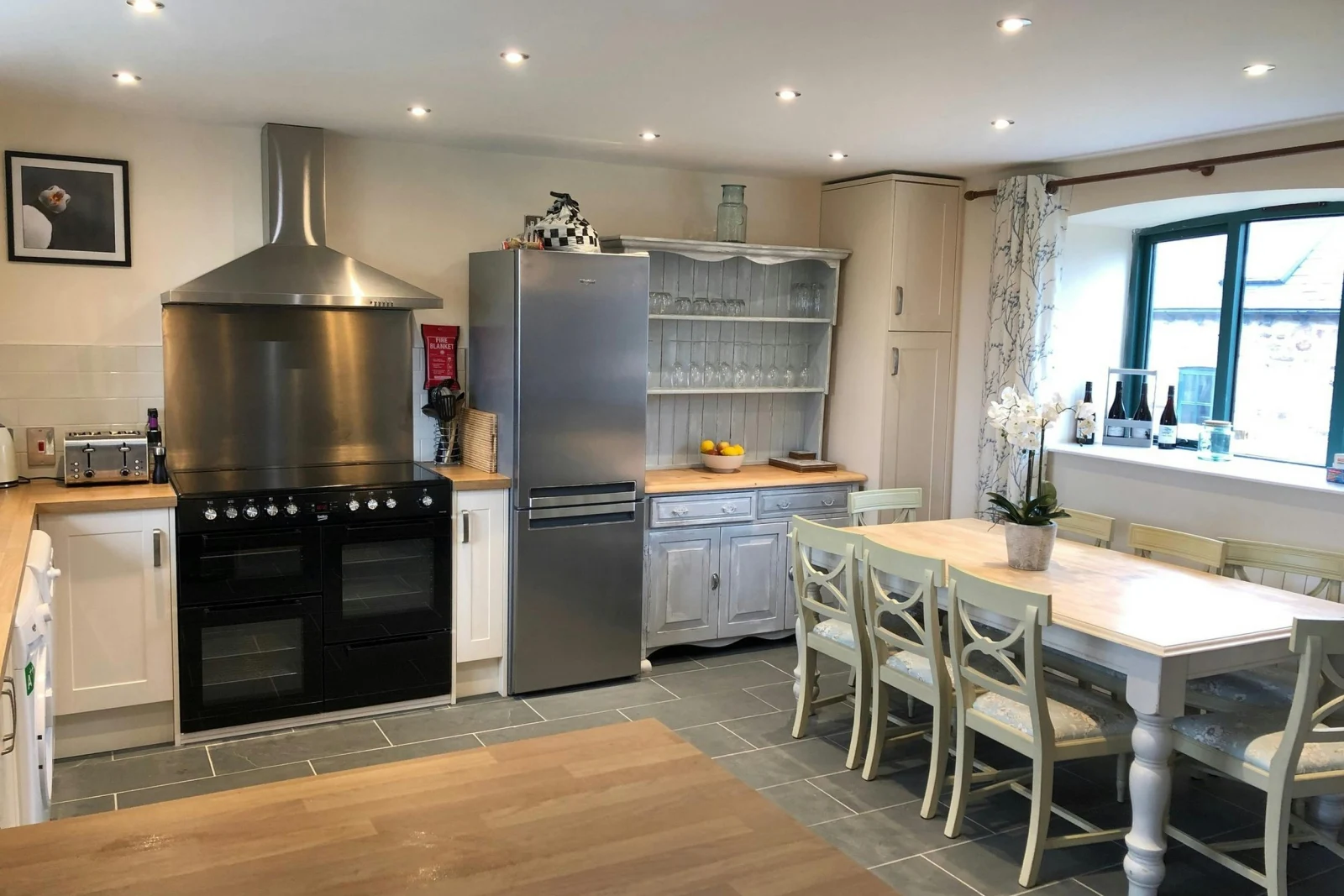 Fitted kitchen with range cooker, fridge/freezer, toaster, kettle and washing machine: dining table with 8 chairs