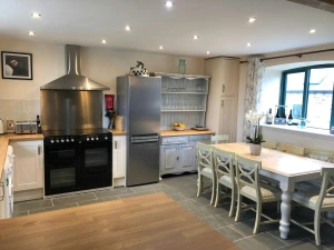Fitted kitchen with range cooker, fridge/freezer, toaster, kettle and washing machine: dining table with 8 chairs