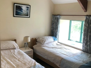 Bedroom with twin single beds, bedside drawers and lamp, low window