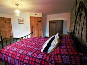 King size bed covered in a Welsh blanket, wardrobe and cushions on the bed