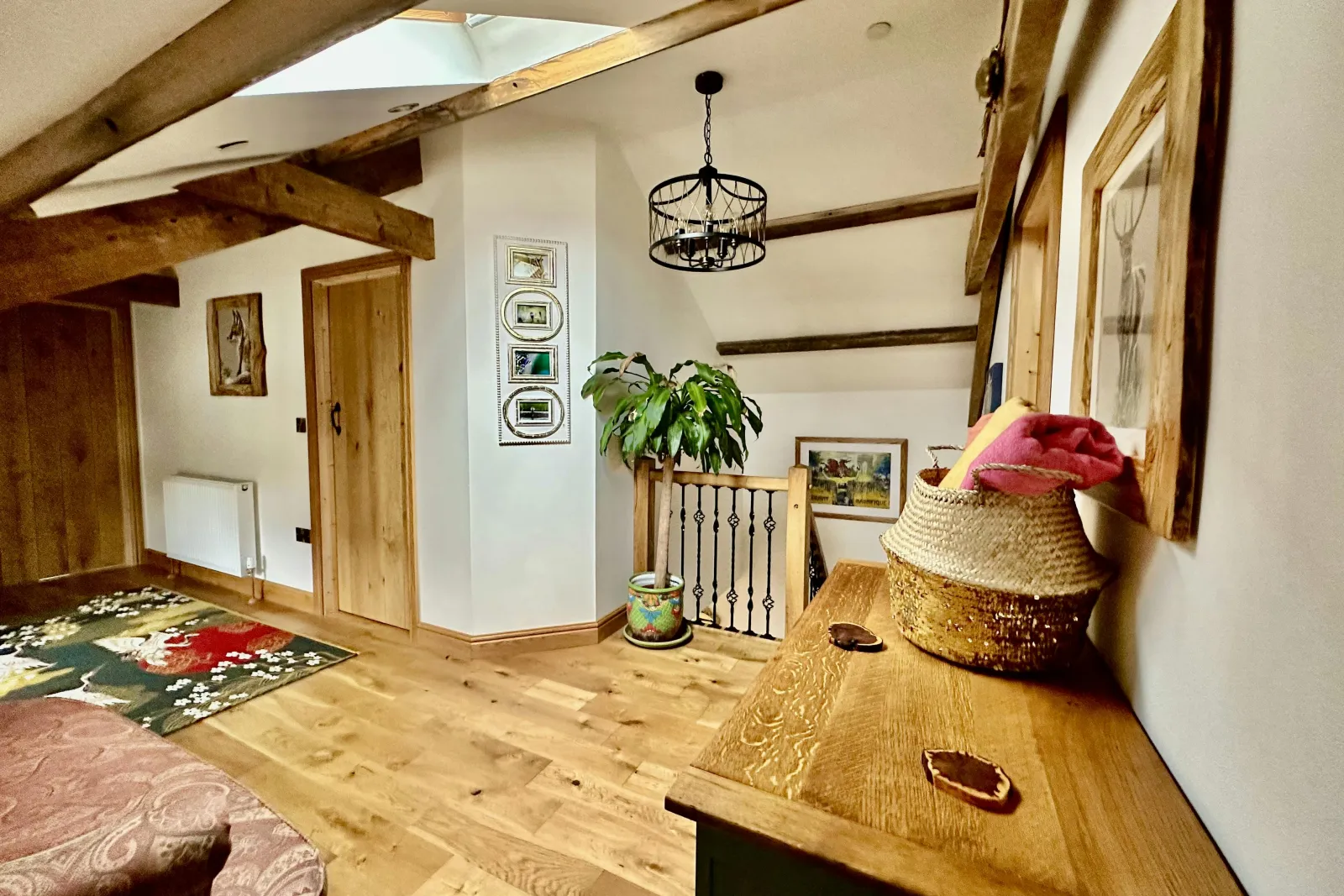 Landing area, sideboard, tall plant in patterned pot, doors leading to bedrooms. rug in the middle