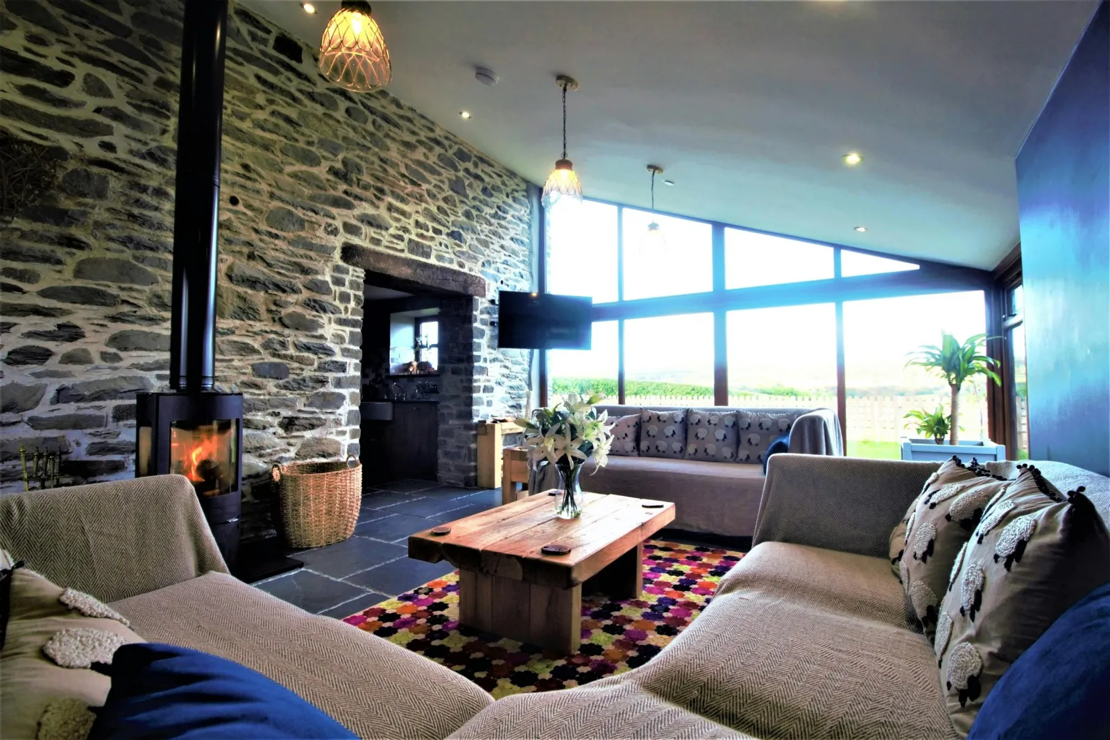 Corner sofa, sofa, coffee table with vase of flowers and wood burning stove