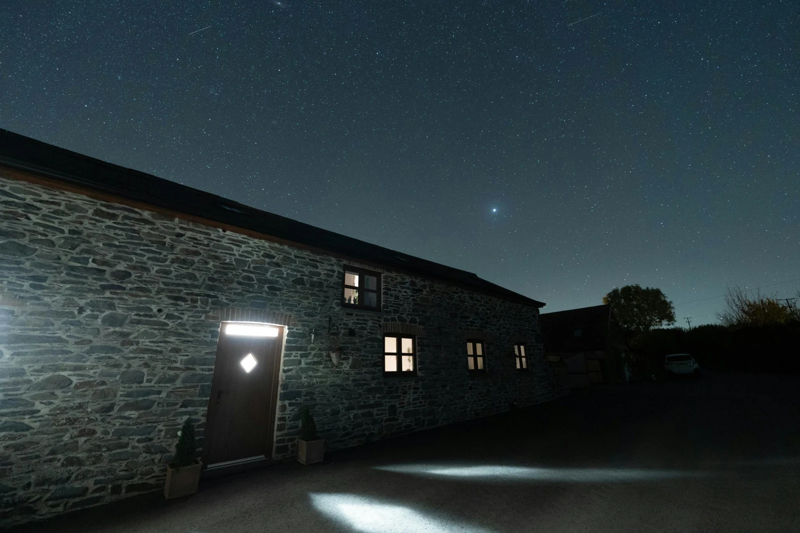 night time photo of the outside of the cottage, sky full of bright stars.