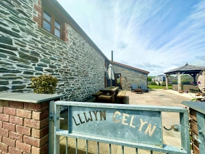 gate to cottage with name on and patio area with picnic bench, pergola and hot tub area
