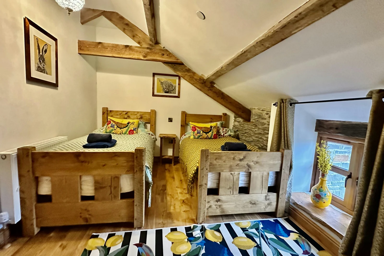 twin bedroom with patterned duvet and rug on floor, bedside table between beds