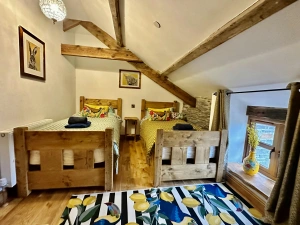twin bedroom with patterned duvet and rug on floor, bedside table between beds